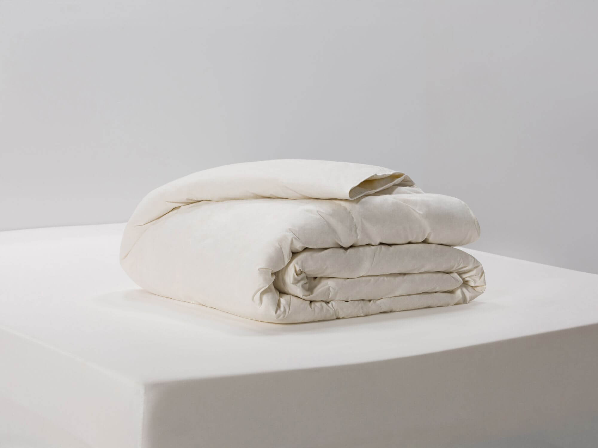 Side angle view of folded ivory down duvet